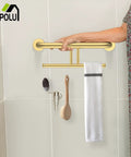 Heavy Duty Brushed Gold Handicap Grab Bar With Integrated Toilet Paper Roll Holder And 304 Stainless Steel Build Offer Kick Ass Grip And Drip Worthy Wall Mounted Bath Safety Rail For Real Ones Who Want Solid Support held by hand in a bathroom.
