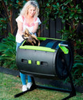 Woman using Two Stage Compost Tumbler For Easy Outdoor Yard Composting Large Eight Point Six Nine Cubic Feet Capacity Rust And Corrosion Resistant Metal And Plastic Construction With Aeration Holes Black And Green Finish Outdoor Use Only Easy Assembly on grass