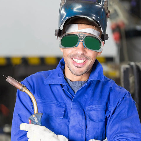 Heavy Duty Welding Safety Goggles With Interchangeable Lenses, Impact Resistant Protective Glasses For Hot Jobs, Built Different Eye Protection, Kickass 3 Pair Set For Workers And Builders worn by smiling welder holding a torch.