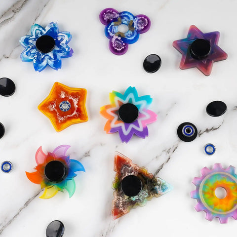 Colorful fidget spinner designs with black end caps and chrome steel bearings, featuring various shapes and colors.