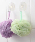 Super Strong Suction Cup Hooks For Bathroom Wall 10 Pack holding purple and green bath loofahs on a smooth white tile surface.