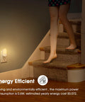 Person walking down stairs with Two Pack LED Night Lights Plugs Into Wall, Dimmable With Light Sensor, Soft White 3000K illuminating steps.