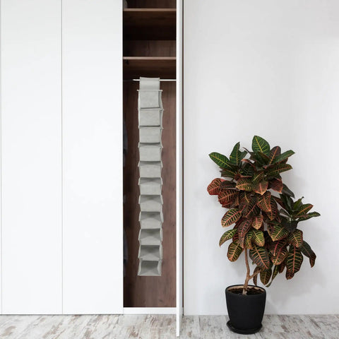 Keep Your Floor Space Sick And Clean With This Hanging Shoe Organizer Bag Featuring Multi Layer Pockets And Solid Nonwoven Material Ideal For Closets Doors And Dorms To Store Every Pair Of Kicks Without Any Hassle in a closet with greenery.