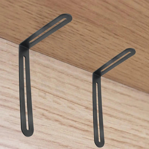 Four Pack Rock Solid Stainless Steel L Shaped Corner Brackets Featuring Dual Adjustable Slide Slots For No Sweat Setup And Heavy Duty Shelf Support Hardware In Smooth Matte Black Finish displayed on wood.