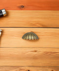 Vintage Shell Cabinet Pulls 4 Pack Antique Bronze Finish Straight Up Heavy Duty Cup Handles on wooden surface.