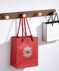 Rock Solid Wall Mounted Coat Rack With Five Hooks For Entryway And Bathroom holds red and white bags on a wooden wall mount.