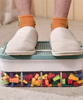 Slick 3 Tier Stackable Brick Storage Organizer With Removable Grid Trays For Lego Pieces, person standing on clear organizer filled with colorful bricks.