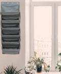 Straight Up Game Changer Over The Door Shoe Rack With Six Roomy Pockets against a wall next to a window with plants.