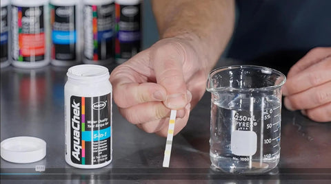 Real Down To Earth Five In One Water Quality Test Strips For Pools And Spas shown with a beaker and testing strip held in hand.