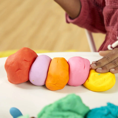 Game Changing Modeling Compound Haul With 65 Mini Cans Serving Up Sixty Varieties Including Rainbow Classics Plus Sparkle Confetti and Color Burst Vibes Ideal for Back to School Supply Lists and Preschool Projects for Kids Two Plus showing bright colored clay lumps arranged on a surface.