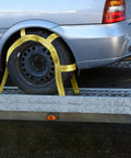 Heavy Duty Tow Dolly Basket Straps Two Pack With Flat Steel Hooks For 15 To 19 Inch Car Tires securing a wheel on a trailer.