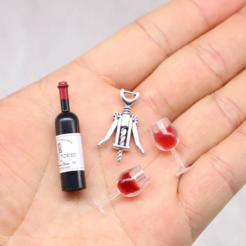 Hella Cool Miniature Red Wine Bottle Set featuring two resin filled wine glasses and a corkscrew on a hand.