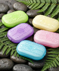 Grab and Go Disposable Soap Sheets Set, 5 colorful boxes on wet rocks with ferns, perfect for travel and outdoor adventures.