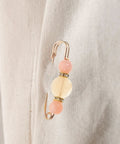 Close-up of a 12 Piece Heavy Duty Alloy Waist Adjustment Pin With Beads on a Fabric Surface for Fixing Baggy Jeans.