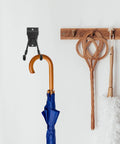 Rock Solid Black Metal Wall Hooks For Bags And Hats With Heavy Duty Mount displaying a blue umbrella on a white wall.