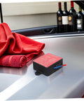 No Sweat Auto Rescue 30G Fire Extinguisher With Super Sticky Back Adhesive For Sedans Trucks And Trailers on car surface beside red towel.