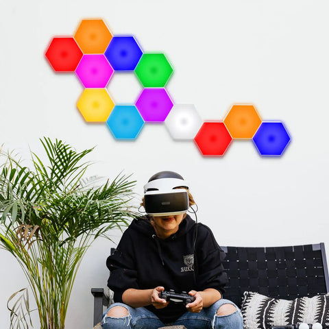 Hexagon LED Wall Panels 10 Pack With Remote And Touch Control RGB 13 Color Lights arranged on a wall above a seated person.