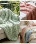 Chunky knitted blankets in pastel colors displayed on sofas and beds