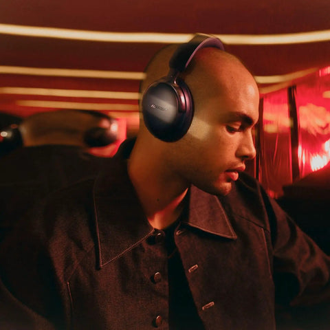 QuietComfort Ultra Bluetooth Headphones Second Gen With Spatial Audio And Wireless Over Ear Noise Cancelling Mic worn by a person in a dimly lit room