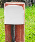 2 Piece Weatherproof Outlet Boxes Tough As Nails ABS Wall Plug Covers Socket Rain Shield mounted on a wooden post outdoors.