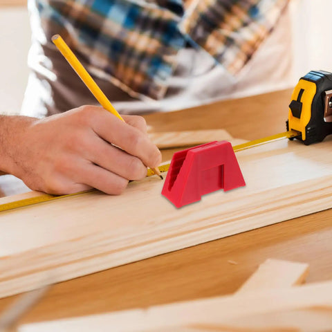 Person measuring wood with tape measure beside a small red plastic tool on a workbench