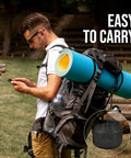 Man carrying backpack with attached camping gear and Stovetop Camping Kettle 2.2 Liter Teapot for Boiling Water and Tea Brewing