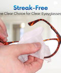 Eyeglass lens wipe; close-up of hand cleaning tortoiseshell eyeglasses with a white wipe