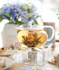 Kyoto 2-In-1 Tea Kettle And Tea Maker Glass Teapot With Removable Loose-Leaf Infuser brewing blooming tea on a table setting.