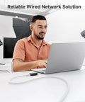 Man using laptop with 10Gbps Snagless Shielded Cat6a Ethernet Cable 10ft White Built For Lightning Fast Home Office Networks Premium Shielded RJ45 Cord