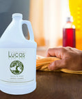 Acrylic Cleaner Spray For Plexiglass And Non Porous Surfaces Streak Free Ready To Use Formula Alcohol And Ammonia Free For Windows Mirrors Electronics Salon And Spa Safe Tanning Bed Friendly 1 Gallon bottle on table with hand wiping surface