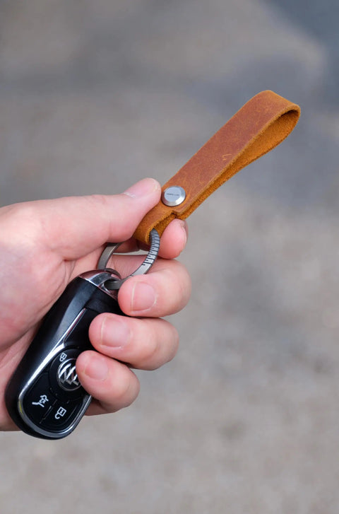Hand holding Top Shelf Crazy Horse Leather EDC Keychain Strap With Aerospace Titanium Key Ring For Car Keys.