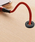 Hella Durable Rubber Cable Grommets 12 Piece Pack Clean Work Desk Cable Management Kit 1 2 Inch Flexible Wire Hole Covers No Snag Desk Patch Black showing black grommet with red wire on wood desk.