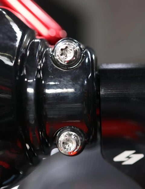Close-up of Top Shelf Titanium Handlebar Clamp Bolts And Brake Clutch Perch Screws For Heavy Duty Motorcycles on a black fork.