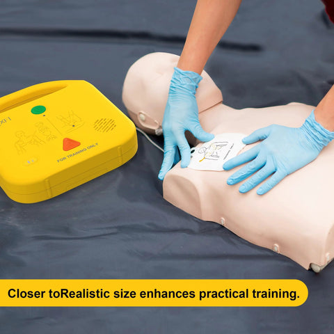 AED trainer device (yellow) with CPR training mannequin and electrode pad being applied by blue-gloved hands.