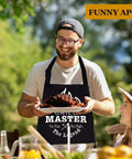 Man wearing 'Grill Master' apron holding barbecued ribs, part of 20 Piece Grilling Accessories Set For Outdoor Barbecue With Apron And Carry Bag Includes Long Spatula Tongs Fork Basting Brush Kabob Skewers Corn Holders Grill Brush And Knife For Dad