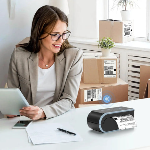 Bluetooth Thermal Label Printer With Built In Paper Bin Wireless Shipping Label Printer For iOS Android Windows Mac ChromeOS USB Or Bluetooth Connection Ideal For Etsy Shopify USPS And Small Biz next to smiling woman in office setting