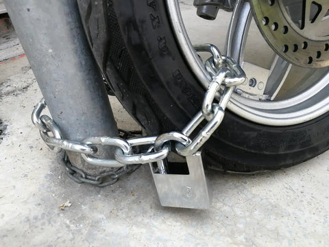 8mm Thick Hardened Steel Chain Lock With Beam Padlock 1.64 Feet Long securing a motorcycle wheel to a metal post.