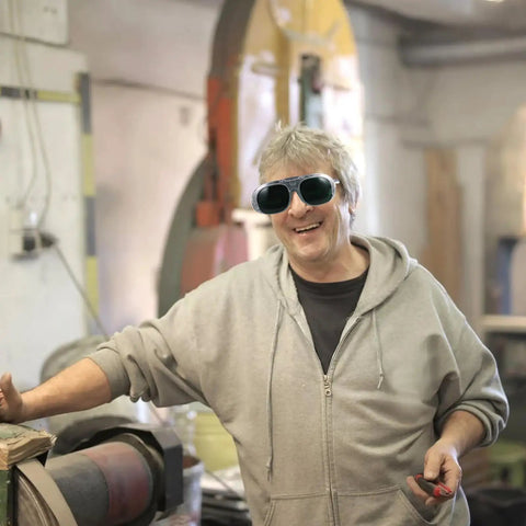 Person wearing Top Shelf Welding Safety Goggles With Heavy Duty ABS Construction And Double Layer Lenses smiling in workshop.