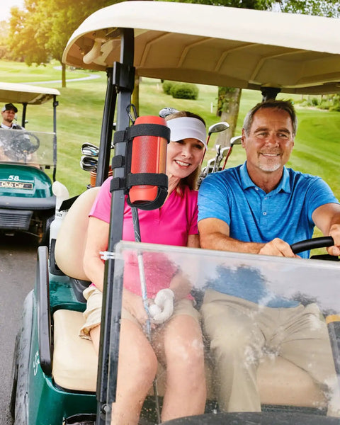 Rugged Portable Speaker Mount With Waterproof Strap for Bluetooth Speakers on golf cart, black, holding an orange speaker.