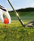 Golfer placing a bright colored mini golf ball on a tee for practice and fun with high visibility for easy tracking outdoors
