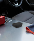 Self Activating Aerosol Car Fire Extinguisher Heat Triggered Auto Engine Bay Suppression Gear on car dashboard with red device.