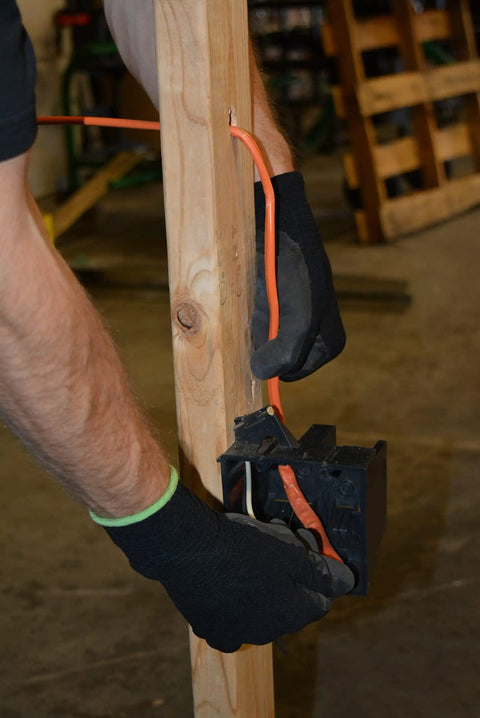 Person installing SIMpull Solid Indoor NM-B Cable 10/2 With Ground Copper Wire for DIY home wiring, connecting to outlet box