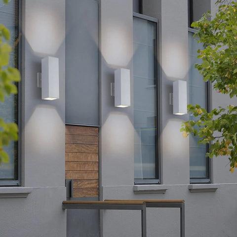 Slick 13 Inch White Square Outdoor Wall Sconce With Uplight And Downlight Tough Aluminum Frame Matte Texture Warm Glow on building facade.