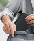 Person reaching for Legit Eva Hardshell Power Bank Case With Heavy Duty Zipper in a gray bag, showcasing its sleek design.