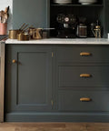 10 Pack 3 Inch Antique Brass Cabinet Pulls Swanky Bin Cup Drawer Handles on kitchen cabinetry with dark green finish.