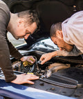 Two men working on a car engine, possible use of Internal Tooth Lock Washers Assortment Kit With Star Shape 300 Pcs Stainless Steel in repairs.