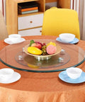 Large Round Clear Tempered Glass Lazy Susan Turntable on a table with fruit bowl and dinnerware for serving at gatherings.