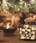 Foldable Firewood Rack For Indoor And Outdoor Use, Rust-Resistant, holding logs at a patio gathering, surrounded by people enjoying an evening.