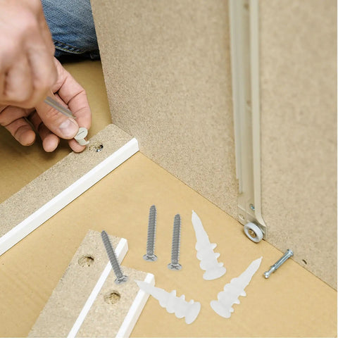 Person installing Heavy Duty Wall Anchors And Screws Kit, 50 Sets, Stainless Steel And Plastic Construction, showing anchors and screws