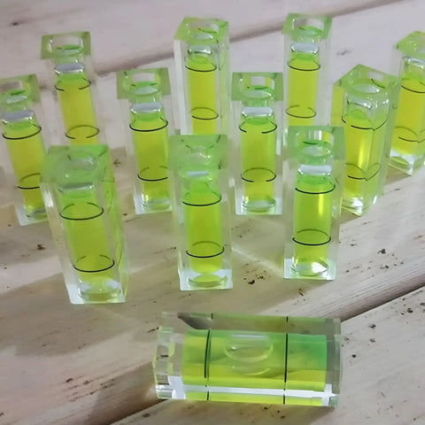6Pcs Small Bubble Level 10x10x29mm Mini Square Spirit Level Picture showing multiple green bubble levels on wooden surface.